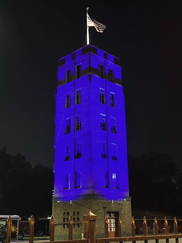 Historic brick tower washed in blue architectural lighting at night